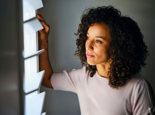 Woman with curly hair looking out a window