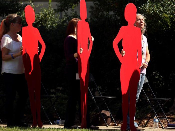 Women standing behind red silhouettes