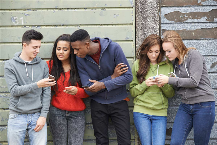 Young people looking at their phones in a group